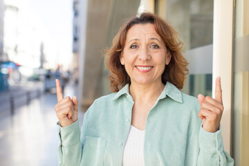 middle age woman feeling awed and open mouthed pointing upwards with a shocked and surprised look