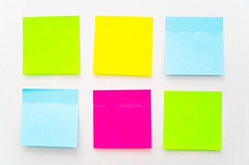 Post it of various colors stuck to a white surface. Notes and memos.