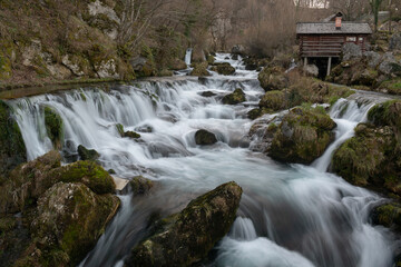 Mountain river with mossy rocks and wooden watermills in long exposure, river Krupa in Krupa na Vrbasu