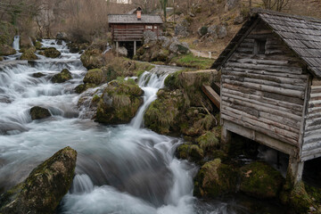 Fototapeta na wymiar Mountain river with mossy rocks and wooden watermills in long exposure, river Krupa in Krupa na Vrbasu