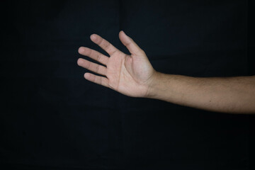 hand of a scared man asking for urgent help on black background_