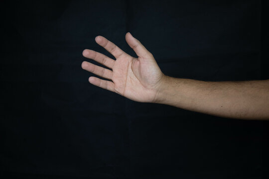 hand of a scared man asking for urgent help on black background_