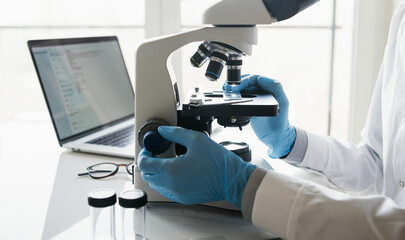 Medical laboratory, scientist hands using microscope for examining samples and liquid, Scientific and healthcare research
