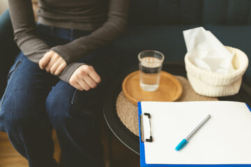 Psychologist's office. Close-up of glass of water, clock and napkins on sofa. Comfortable sofa....