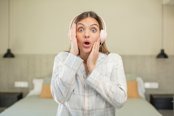 Fototapeta premium young pretty woman feeling extremely shocked and surprised. headphones concept