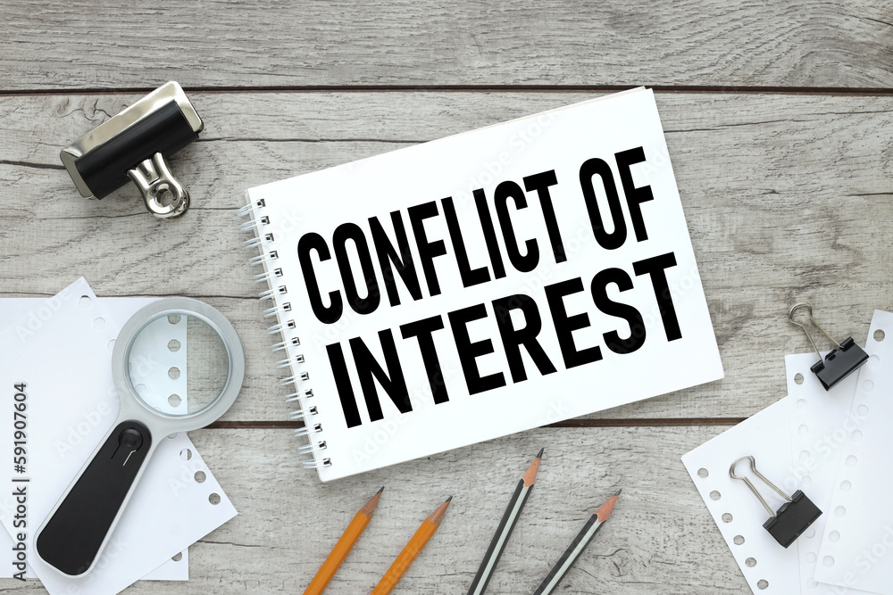 Poster conflict of interest text on a torn page on a table near a magnifying glass. view from above
