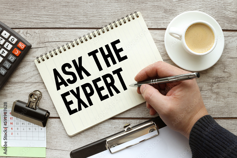 Poster ask an expert text on a white page on the table. a man writes in a notebook
