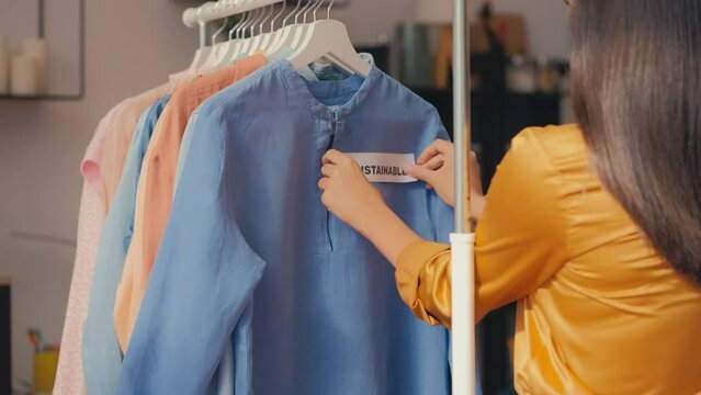 Clothing shop seller putting sustainable label on blouse, eco consumption