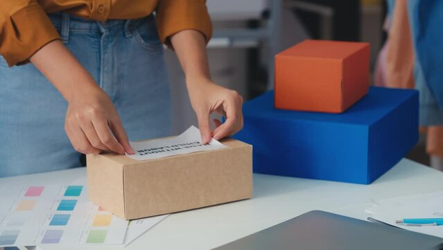 Woman putting made without child labor label on box, responsible production
