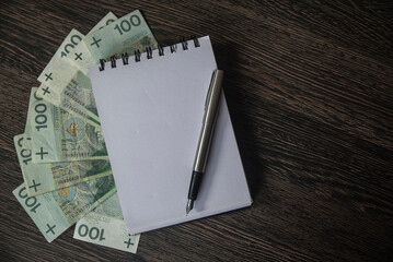 Banknoty, notes oraz pióro leżące na blacie stołu. - obrazy, fototapety, plakaty
