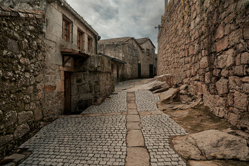 Spanish village street with cobblestones, houses on one side and a wall on the other side of the street