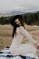 Portrait of a woman traveler in a hat against the backdrop of the snowy Carpathian mountains