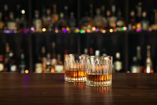close up view of two glasses with whiskey on color back