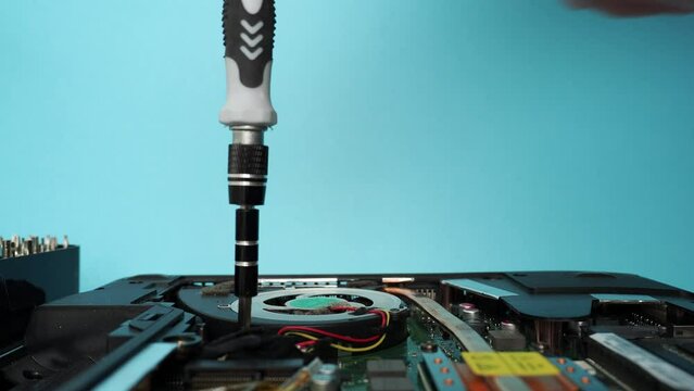 The master repairs a broken laptop with a screwdriver. Specialist and old broken laptop.