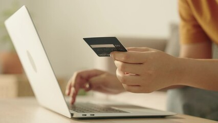 Side view. Hand of young women are buying online with a credit card. woman are using the laptop and doing online transactions at home. Concept of shopping online by technology and lifestyle new normal