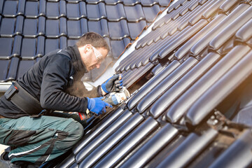 Craftsman using an angle grinder to cut a tile on a roof