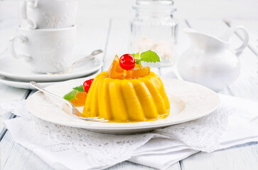 Traditional Italian mango pudding with glaceed cherry served as close-up on a classic design plate