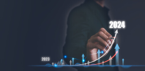 Businessman hand drawing graph line for increasing arrow from 2023 to 2024 for preparation new...