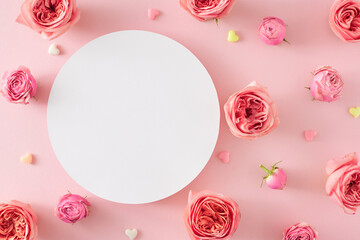 Women's Day atmosphere concept. Creative layout made of empty circle and natural flowers pink rose buds and small hearts on isolated pastel pink background. Flat lay with blank space