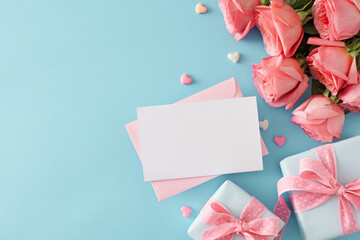 Present concept for Mother's Day. Top view photo of envelope with postcard present boxes bouquet of pink roses and small hearts baubles on pastel blue background with copy space