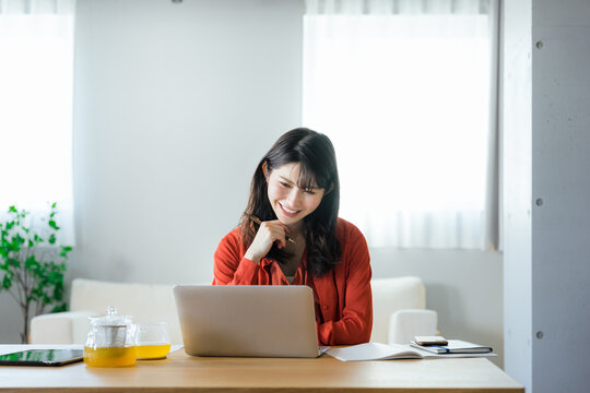 リビングでノートパソコンを使ってオンラインで資格の勉強をしながら考える20代から30代の日本人の女性