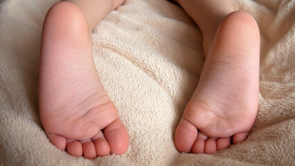 Close-up of two childs feet lying on a soft plaid