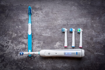 Electric and manual toothbrushes. Top view. Hygiene of the oral cavity. An ordinary toothbrush and electric toothbrush on gray background.