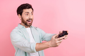 Photo of funky exited man wear turquoise shirt enjoying playstation game empty space isolated pink...