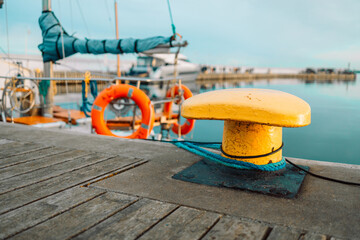 Rope mooring and bollard against the background of sea water and yachts