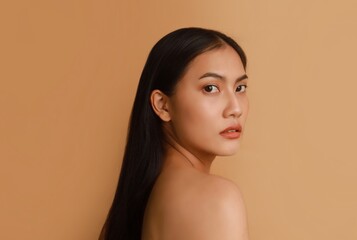 Portrait of beautiful Asian a woman with natural makeup standing over beige background, copy space.
