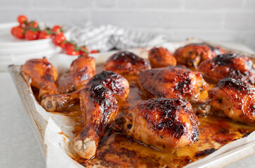 Oven baked and glazed chicken drumsticks and shanks with honey barbecue sauce on a baking sheet on...