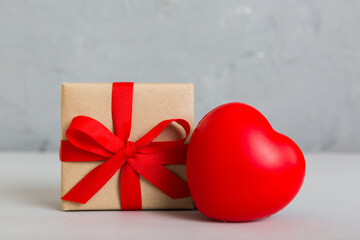 gift box with red bow and red heart on colored background. Perspective view. Flat lay
