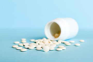 Medicine bottle and white pills spilled on a light background. Medicines and prescription pills flat lay background. White medical pills and tablets spilling out of a drug bottle