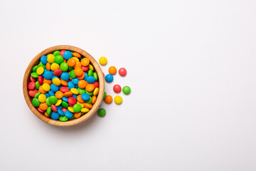 Multicolored candies in a bowl on a colored background. birthday and holiday concept. Top view with copy space