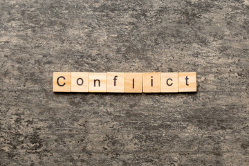 CONFLICT word written on wood block. CONFLICT text on cement table for your desing, concept