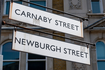 Obraz premium A sign for Carnaby Street and Newburgh Street. Famous tourist and shopping destination in Westminster, London, United Kingdom.