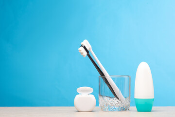 Hygiene. Two toothbrushes in a glass, dental floss and antiperspirant on the table, blue background