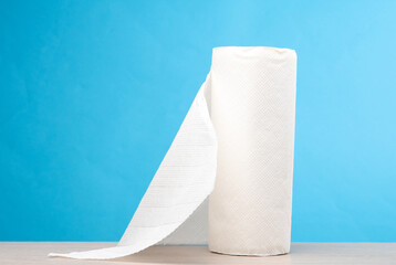 Roll of white paper towels on the table, blue background