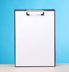 White empty clipboard on the table, blue background. Template for design