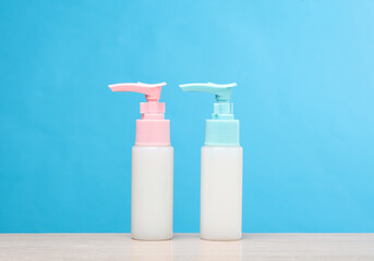 Two bottles of cream dispenser on the table, blue background