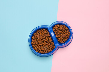 Double bowl of cat food on blue pink background. Top view