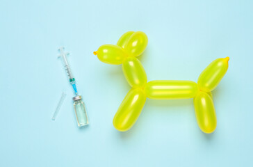 Vaccination of pets, veterinary medicine. Balloon dog and a syringe with a vaccine on a blue background. Top view