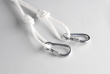 Rope with knots, loops and carabiners on gray background. Safety, climbing equipment