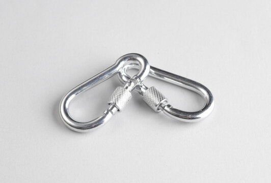 Two metal carabiners on a gray background