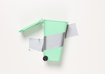 Trash can fixed with adhesive tape on white background. Conceptual pop, contemporary art