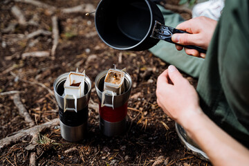 The guy pours boiling water into a glass of coffee, the process of brewing a coffee filter bag in...