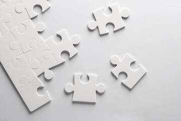 Obraz premium White jigsaw puzzle pieces on a gray background.