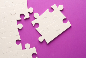 White jigsaw puzzle pieces on purple background.