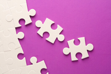 White jigsaw puzzle pieces on purple background.