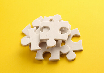 White jigsaw puzzle pieces on yellow background.